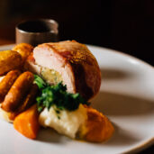 Delicious gourmet roast dinner with succulent pork, potatoes, and vegetables at luxury hotel restaurant.