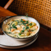 Rustic dining with creamy vegetable soup and brown bread on wood table at cosy hotel restaurant.