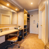 Spacious hotel room with modern desk, flat-screen TV, and warm lighting for a comfortable stay.