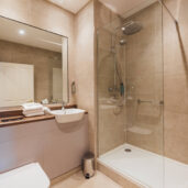 Modern en-suite bathroom with spacious glass shower, elegant countertop, and fresh towels in a luxury London hotel room.