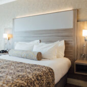 Elegant hotel room with king bed, plush pillows, chic lamps, and warm decor, ideal for a cosy stay in London.
